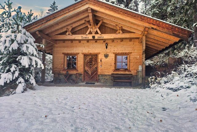 Verschneite Tiroler Hütte zwischen Fichten am Naturpark Karwendel