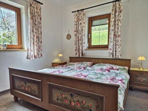 Bemaltes Bauernbett am Fenster im Ferienhaus Alpenrehblick