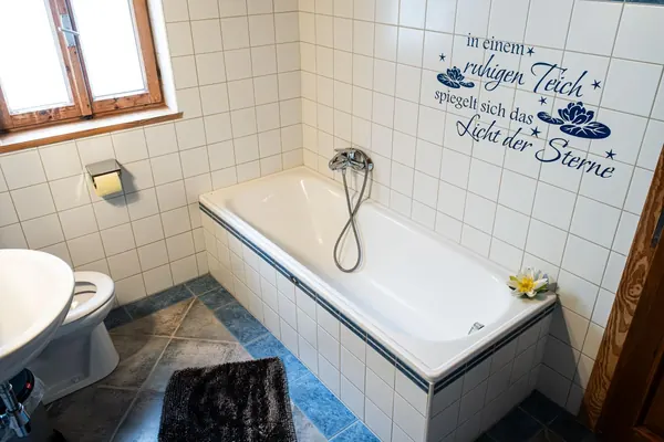 Badezimmer mit Wanne und Spruch an der Wand im Ferienhaus Grafenhäusl