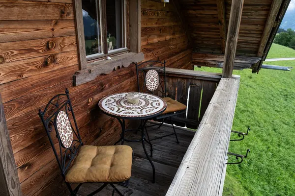Balkon des Grafenhäusl mit zwei Sesseln und Tischchen über der Bergwiese