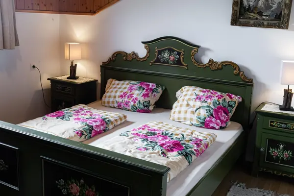 Grün bemaltes Bauernbett mit Blumenwäsche im Grafenhäusl