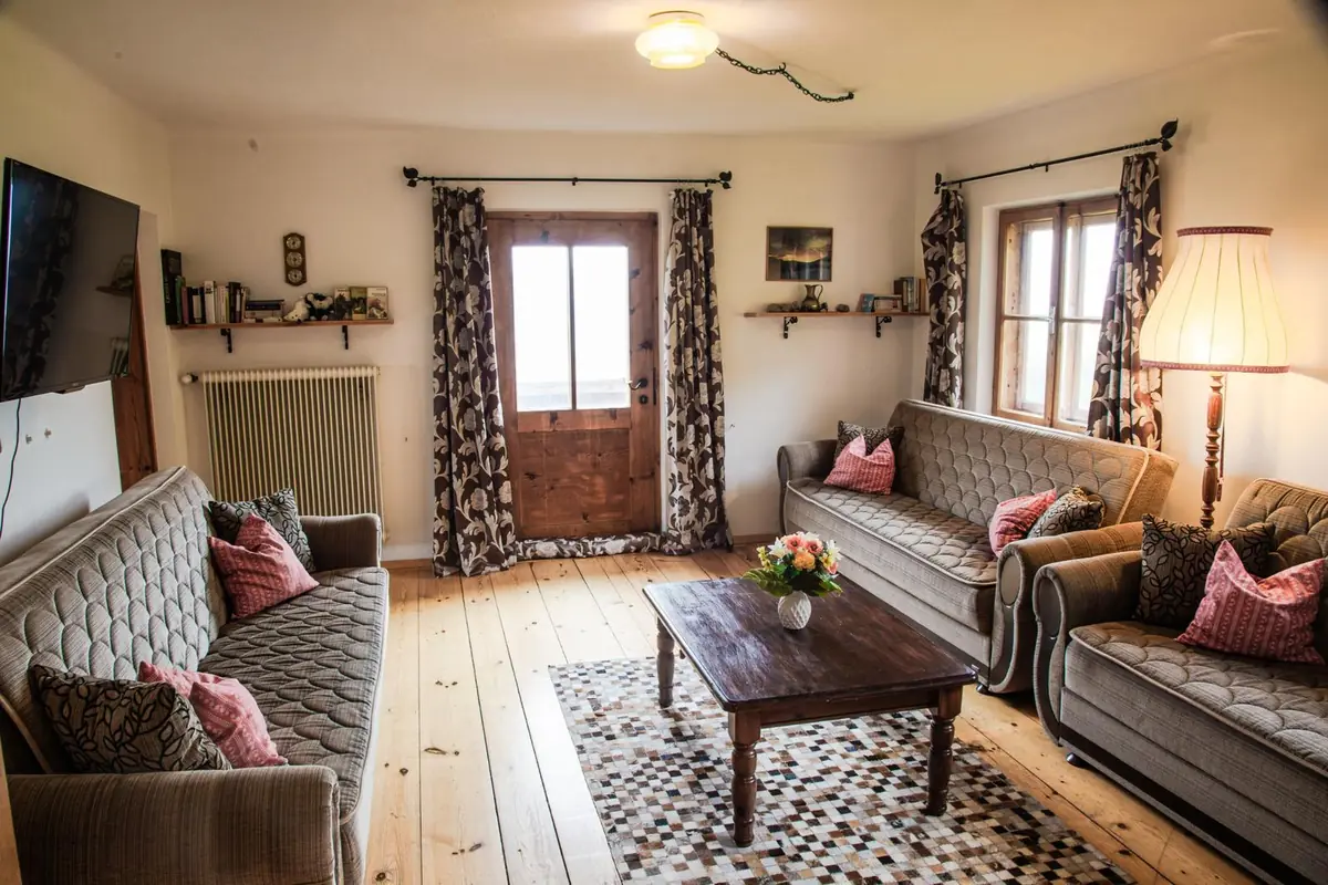 Wohnzimmer im Grafenhäusl mit Dielenboden, zwei Sofas und Blick in den Garten