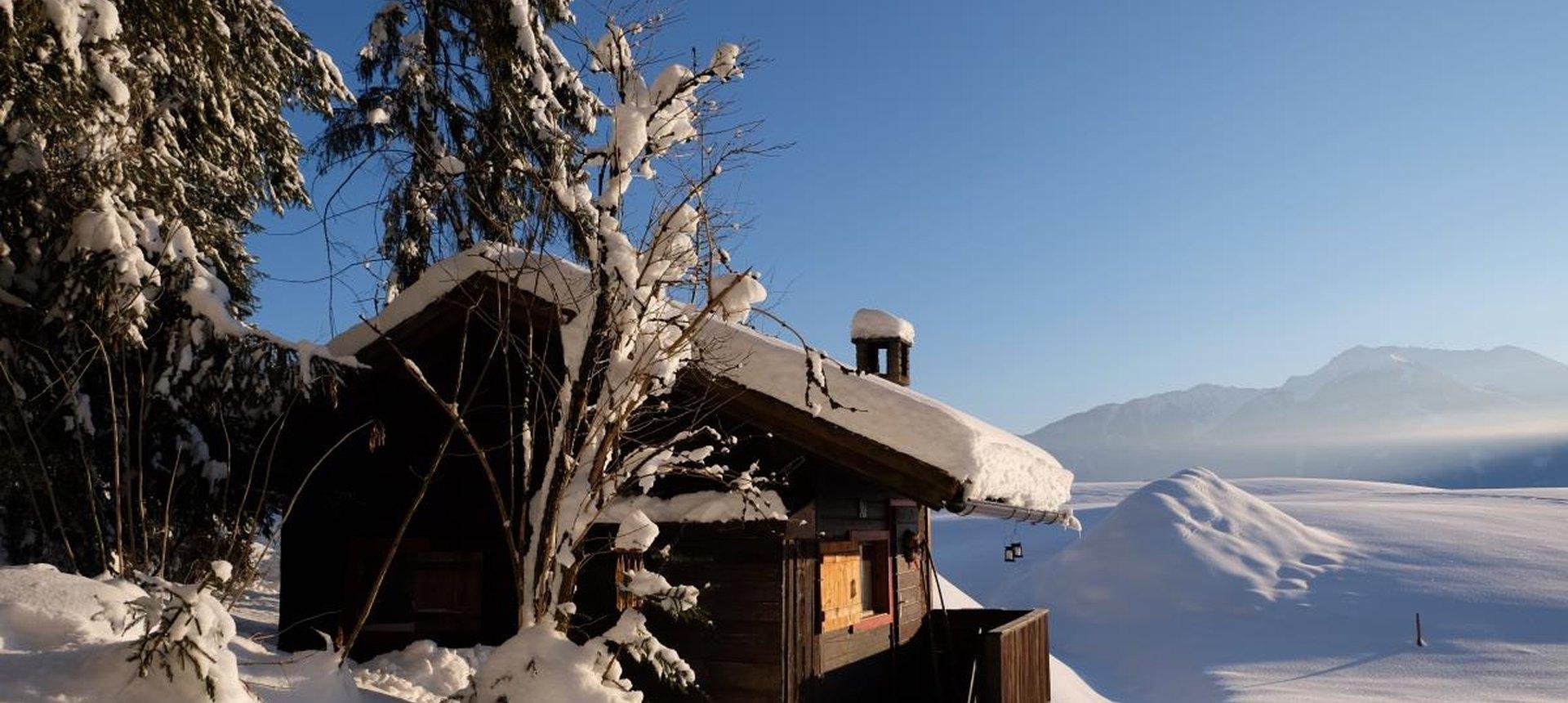 Waldhüttl tief verschneit im Winterwald, einsame Hütte in Tirol