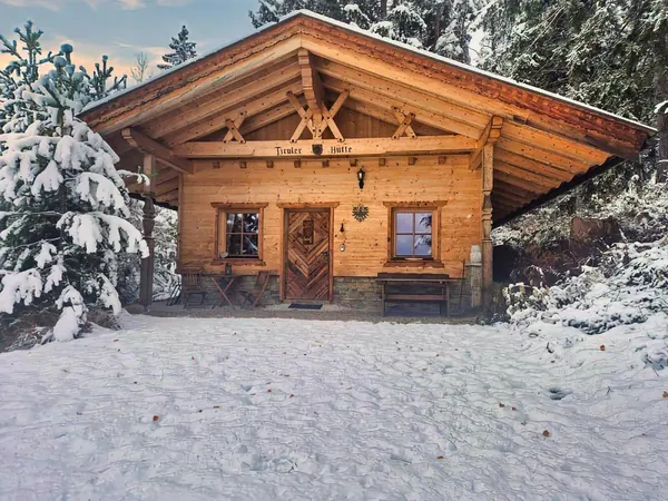 Tiroler Hütte im Schnee zwischen verschneiten Fichten am Umlberg bei Terfens