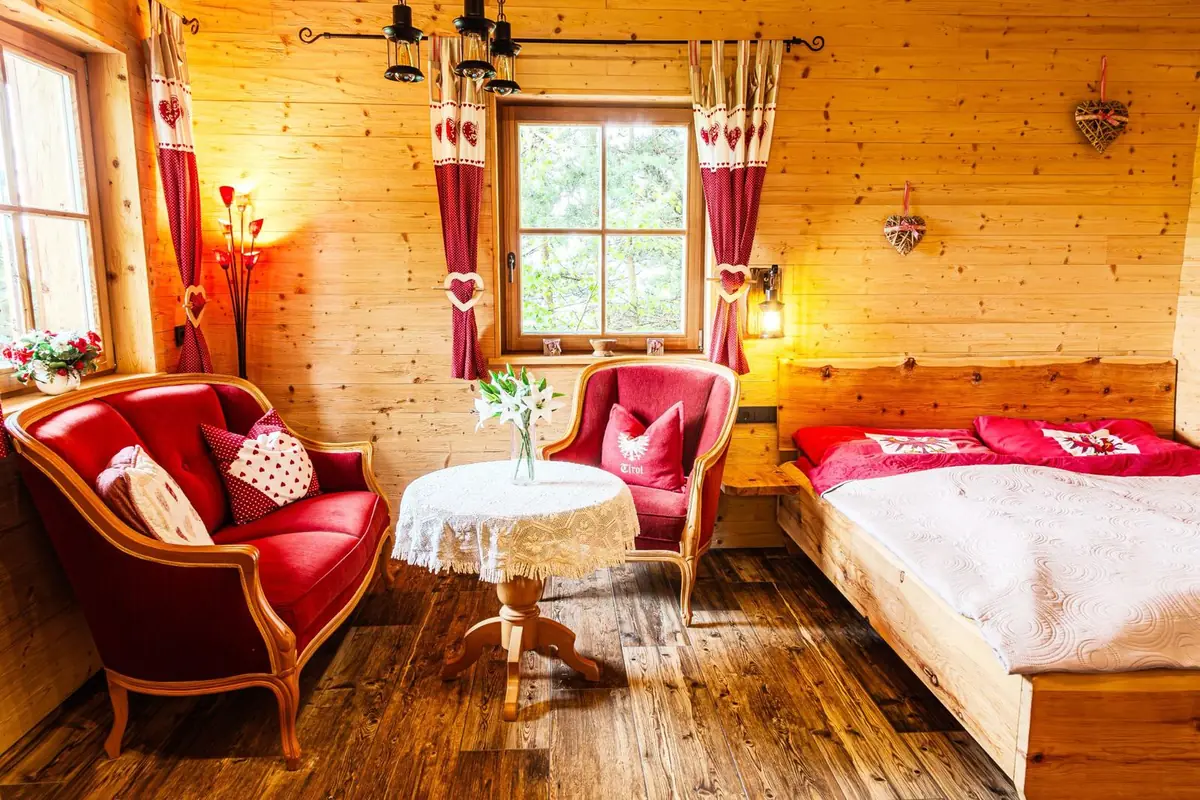 Zirbenholzbett und rote Sessel in der Tiroler Hütte, Almhütte für zwei in Tirol