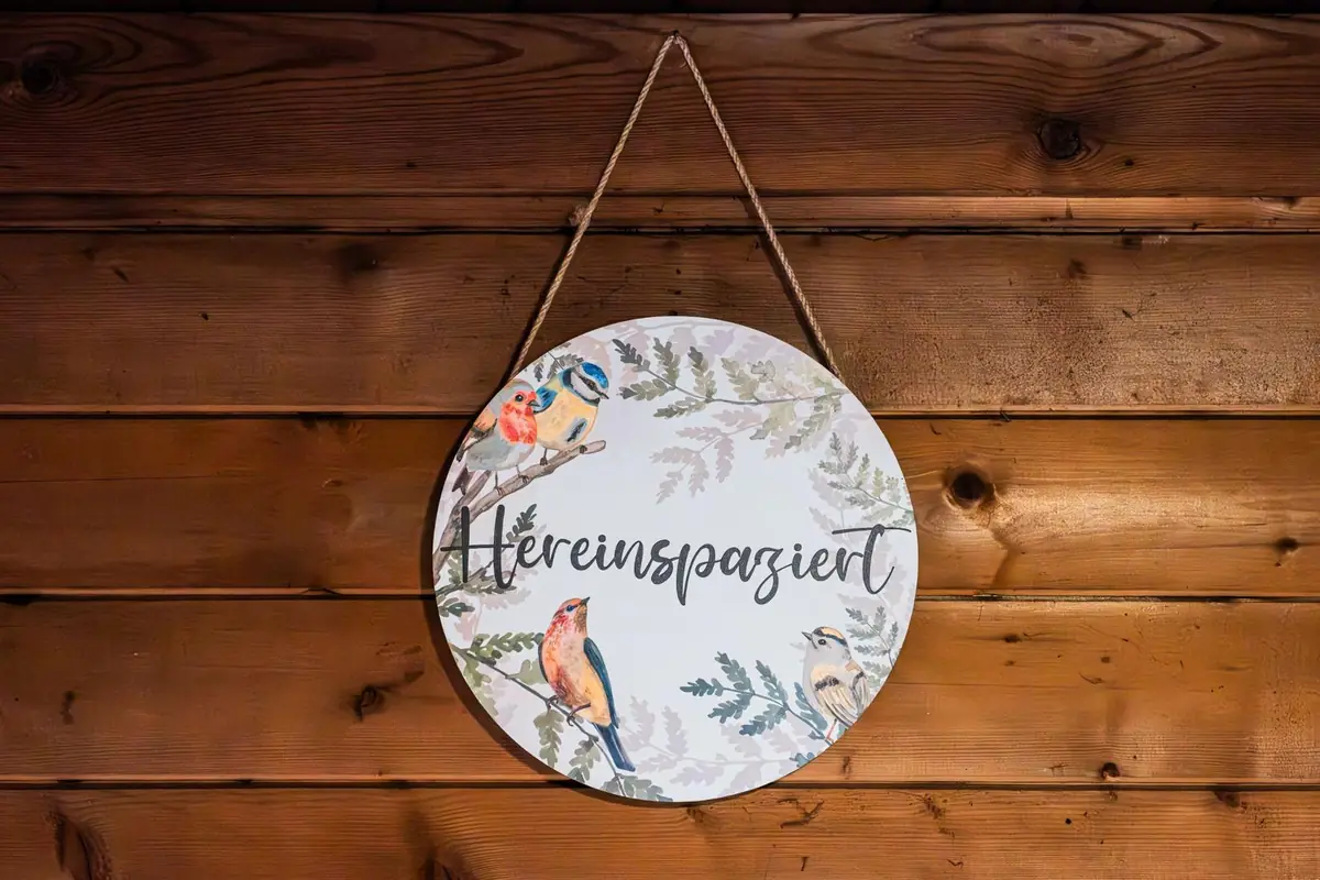 Schild „Hereinspaziert" an der Holzwand des Waldhüttl